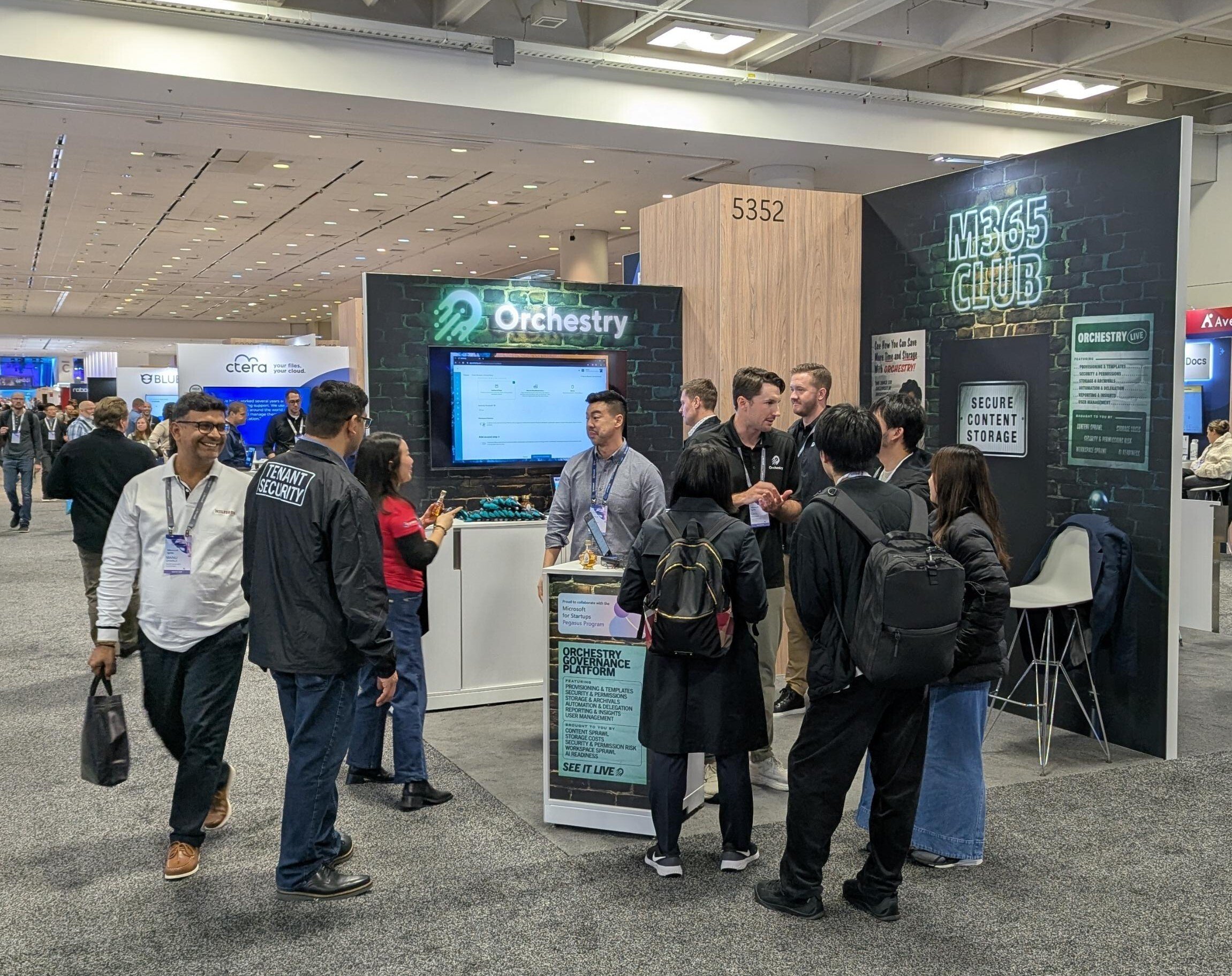 Orchestry booth at Microsoft Ignite 2025 with attendees gathered for a demo.